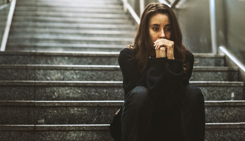 A woman sitting on the stairs with her hand on her face.