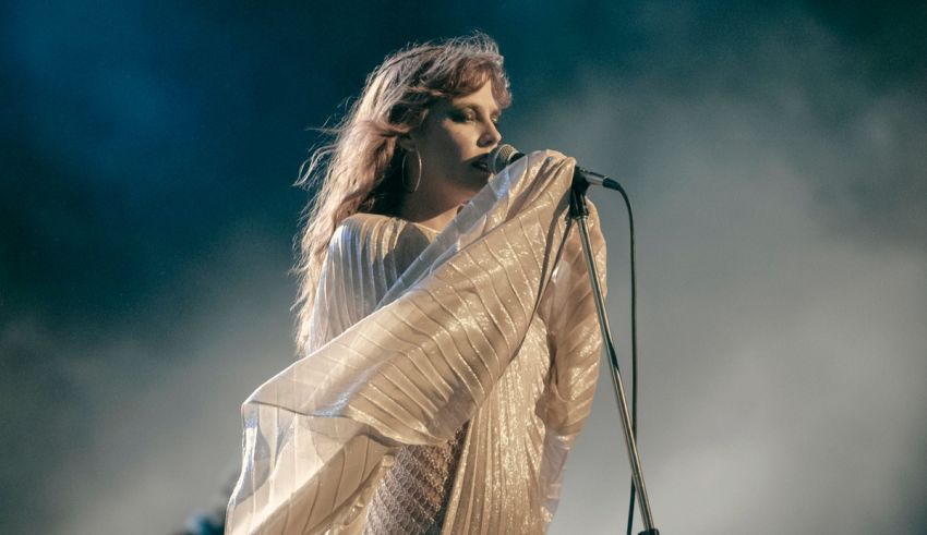 A woman in a white dress singing into a microphone.