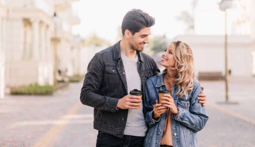 Young man and woman holding coffee in the street.