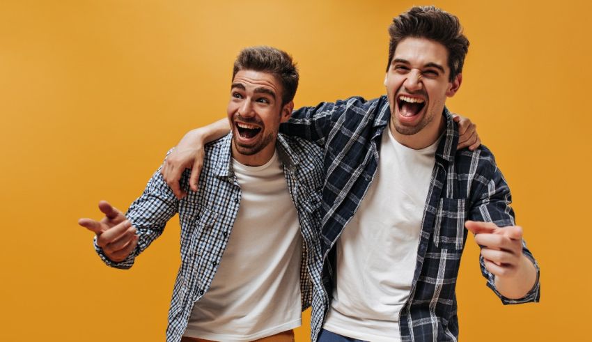 Two young men pointing at each other on a yellow background.