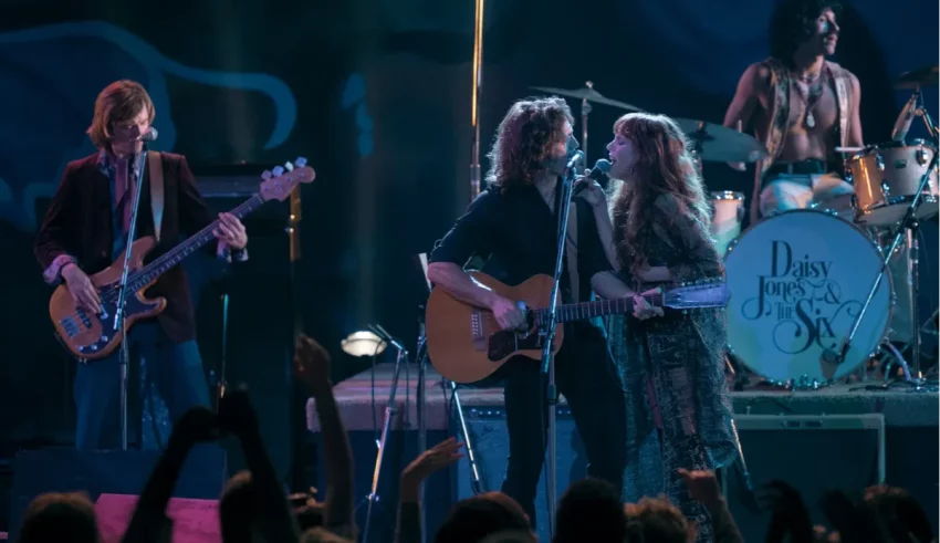 A group of people on stage with guitars and drums.