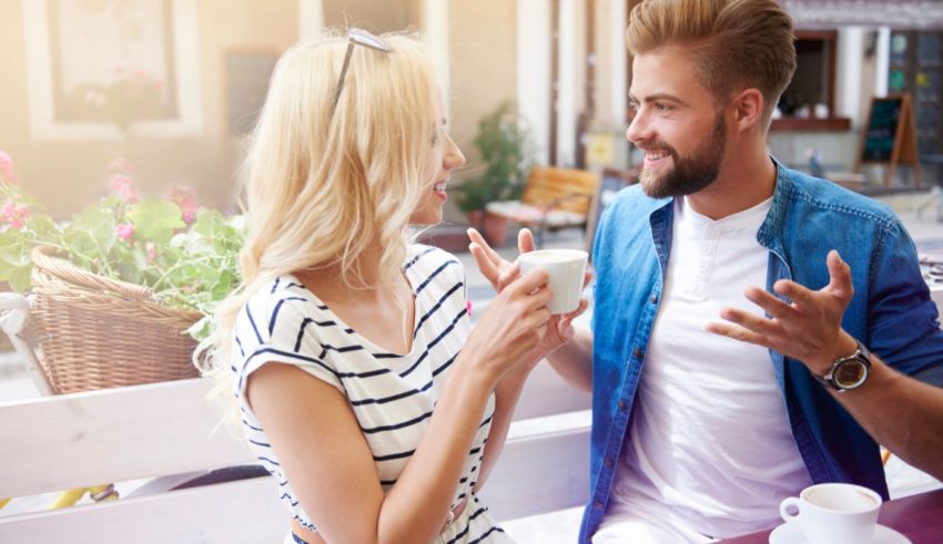 A man and woman are having a conversation at an outdoor cafe.