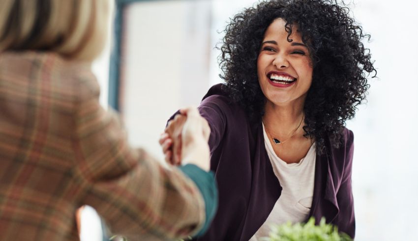 A woman shakes hands with another woman in an office.