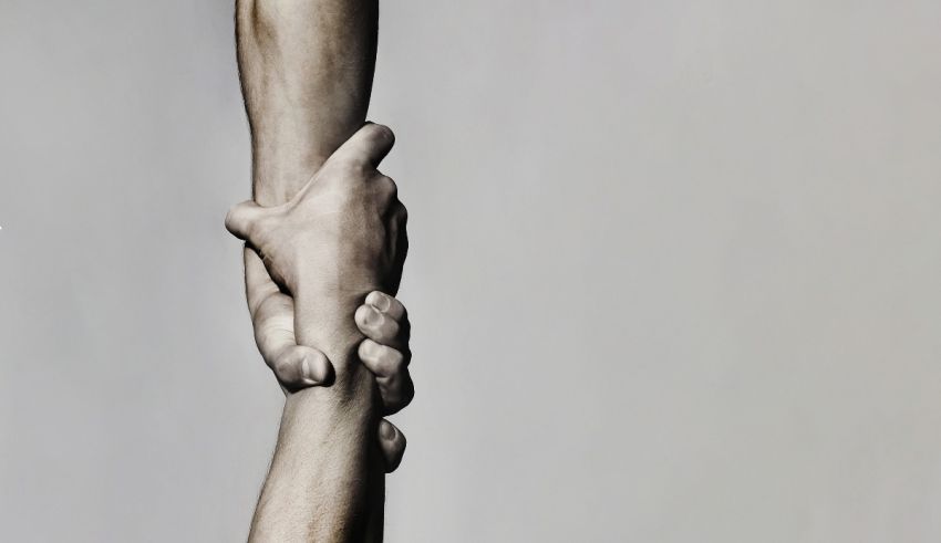 A black and white image of two hands holding each other.