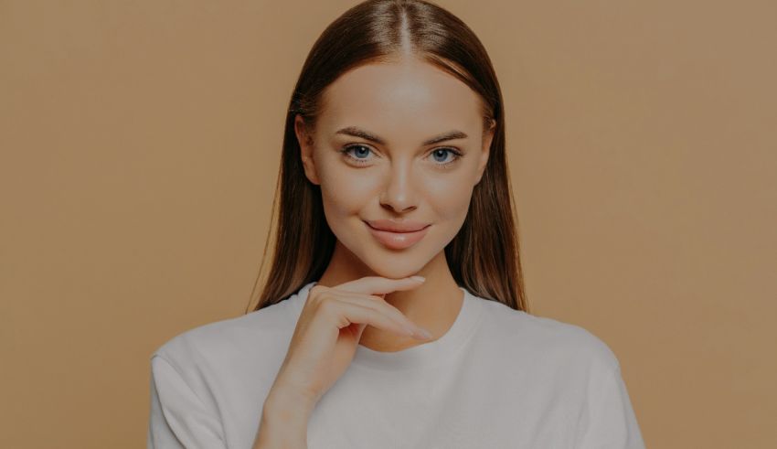 A young woman in a white t - shirt posing on a beige background.