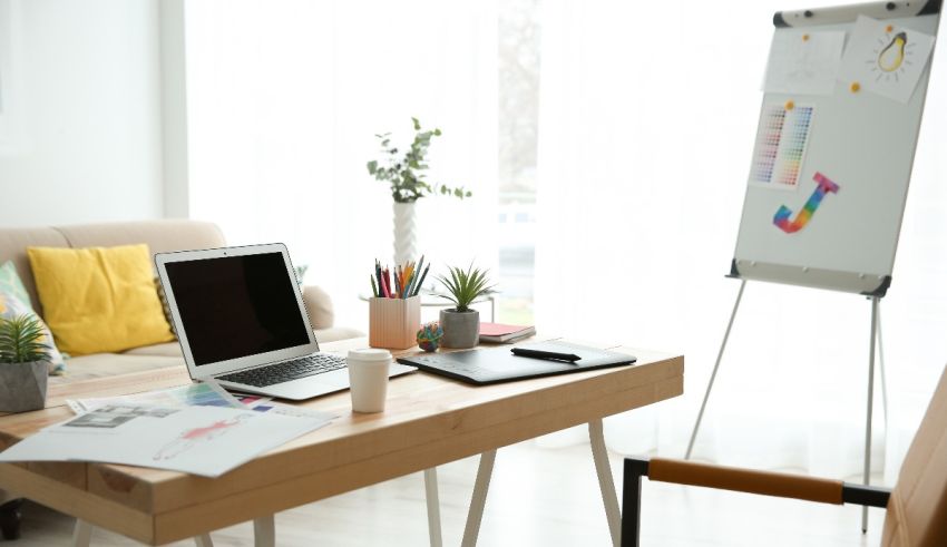 A home office with a laptop and a white board.