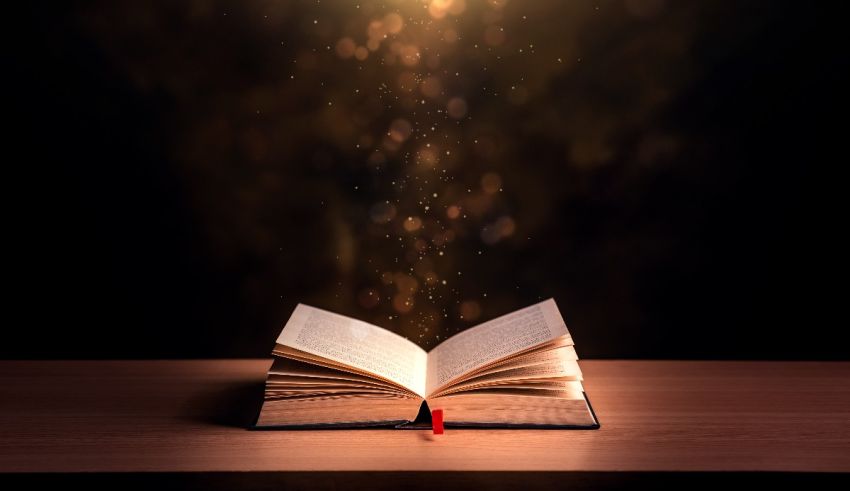 An open book on a table with light coming out of it.