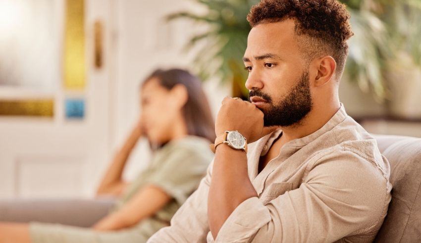 A man sitting on a couch with a woman looking at him.