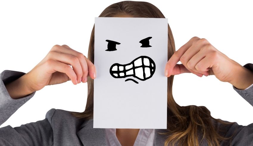 A woman holding up a piece of paper with an angry face drawn on it.