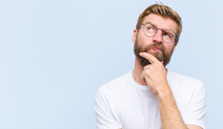 A man with glasses and a beard is thinking about something.