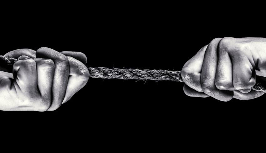 Two hands holding a rope on a black background.