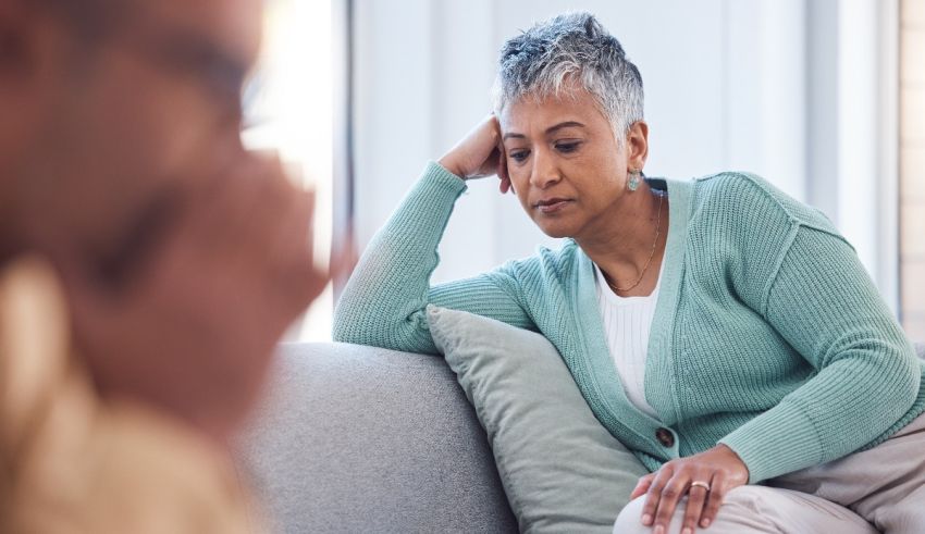 A woman is sitting on a couch and talking to a man.
