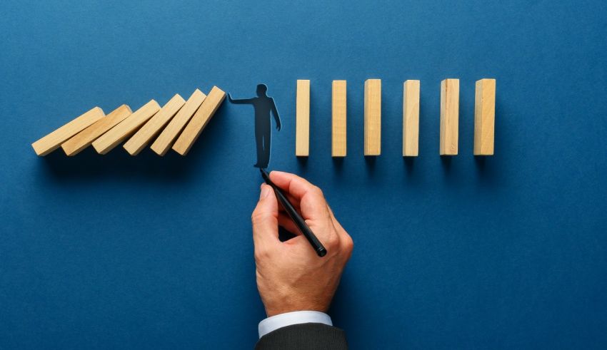 A businessman is putting dominoes on a blue background.