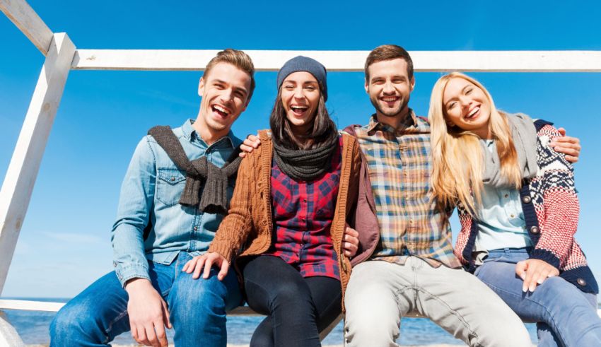 A group of friends sitting on a bench at the beach.
