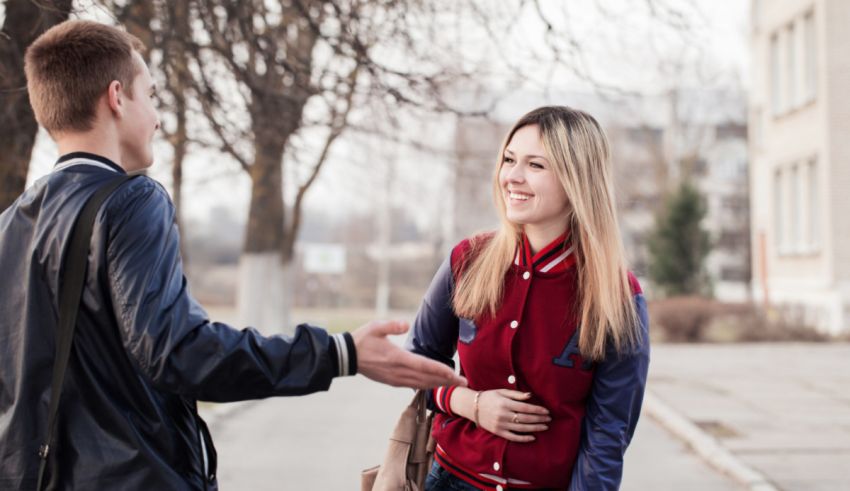A young man and a young woman shaking hands in the street.