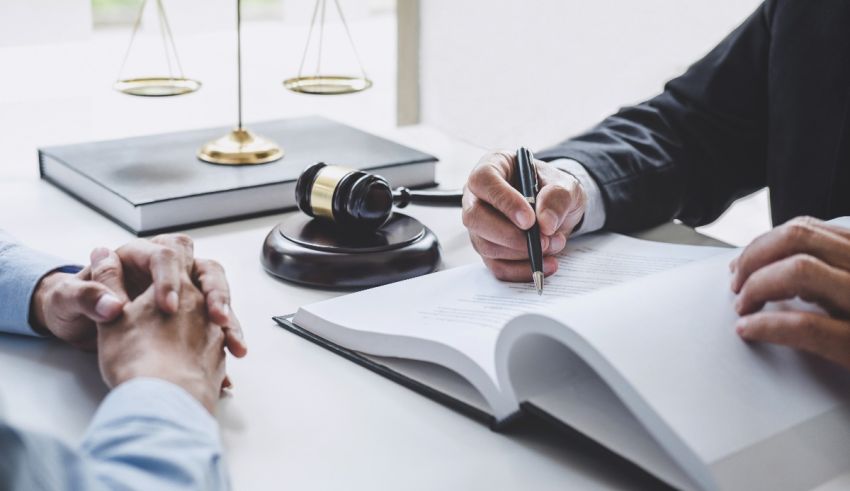 A lawyer signing a document with a judge's gavel.