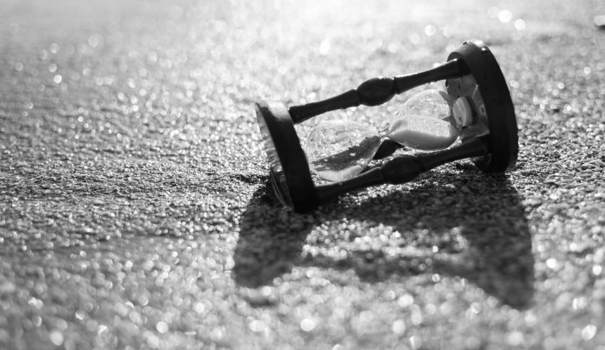 A black and white photo of a clock on the ground.