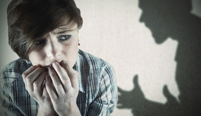 A woman is holding her mouth in front of a shadow of a man.