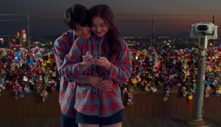 A couple embracing in front of a cityscape.