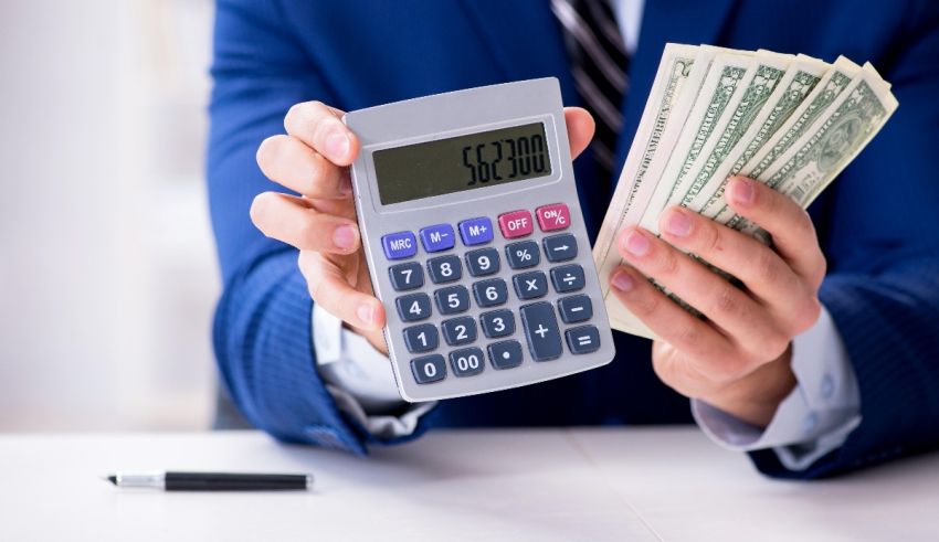 A businessman holding a calculator and money.