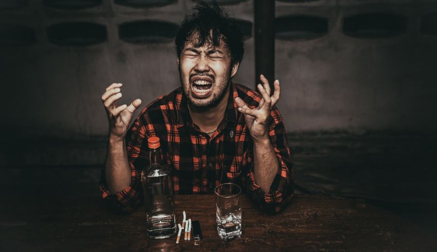 A man is sitting at a table with a glass of alcohol.