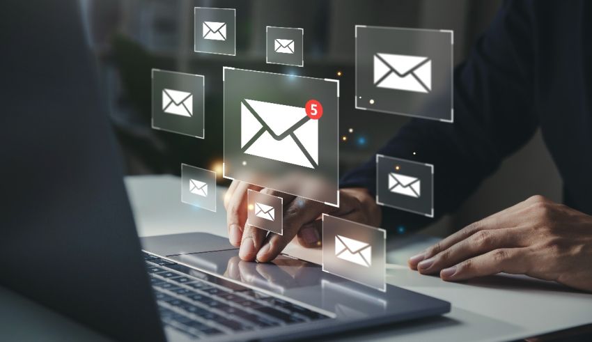 A man using a laptop with email icons on it.