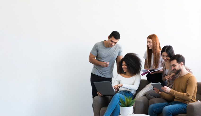 A group of people sitting on a couch looking at a laptop.