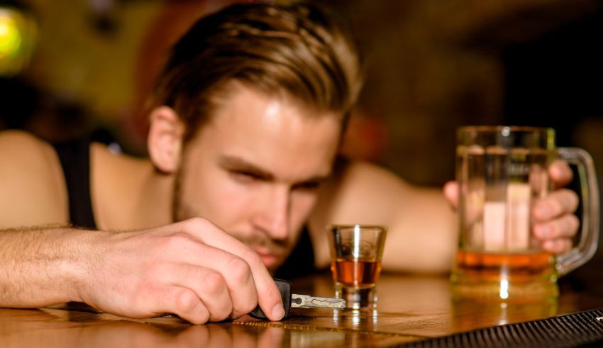 A man holding a shot glass and a bottle of beer.
