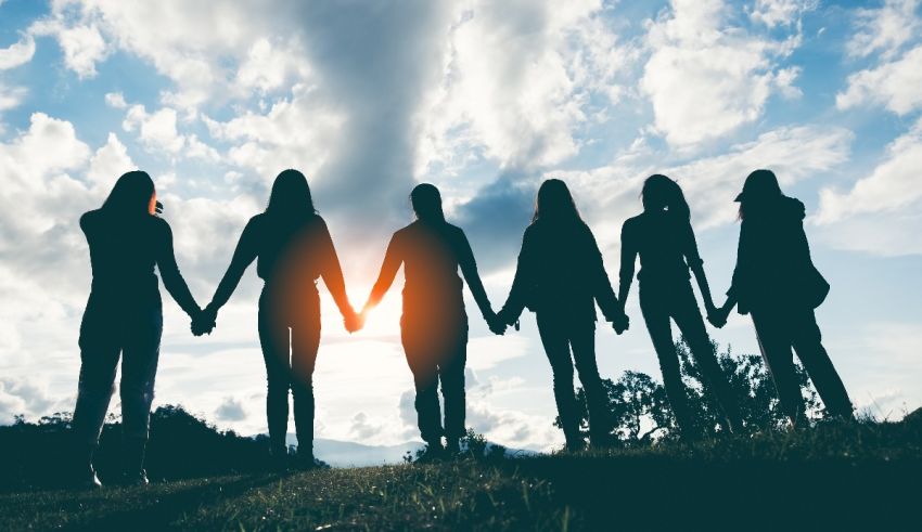 Silhouettes of people holding hands on a hill.