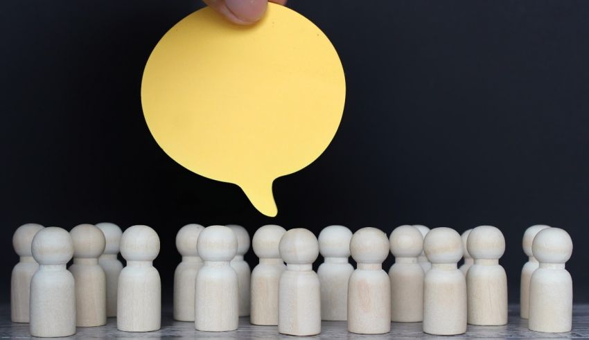 A person is holding a yellow paper in front of a group of wooden figures.