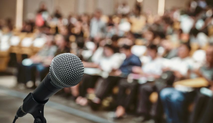 A microphone in front of an audience in a conference hall.