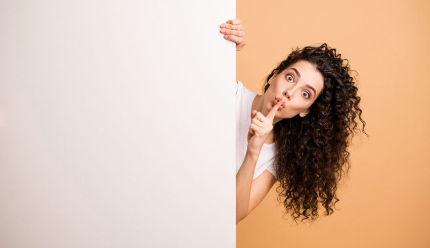 A young woman hiding behind a white board.