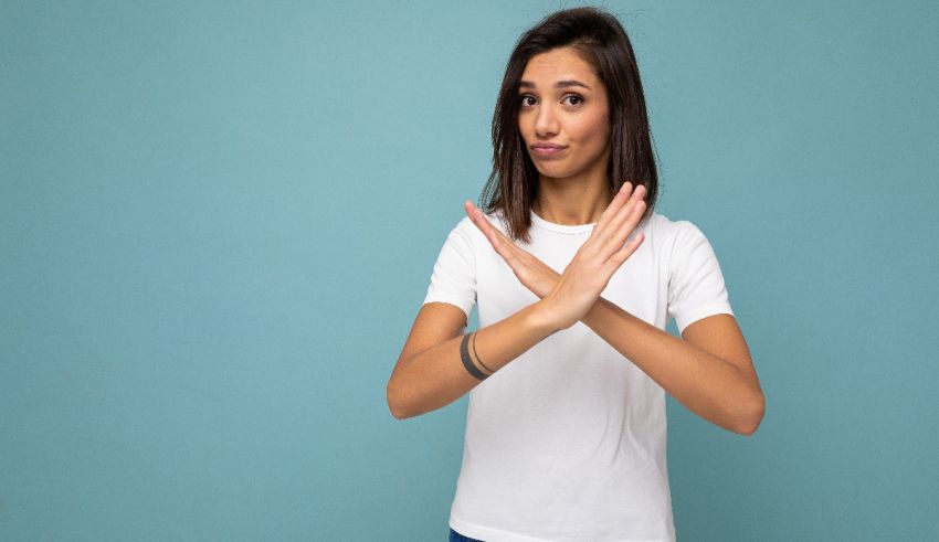 A young woman making a stop sign against a blue background.