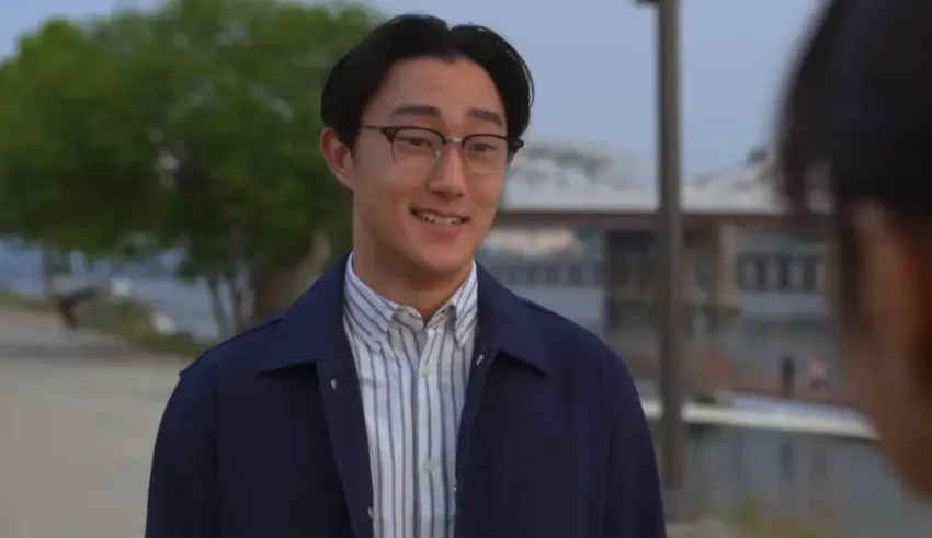 A man in glasses is talking to a woman in a blue jacket.