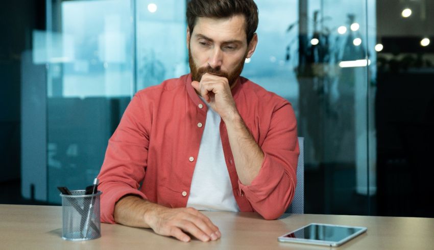 A man with a beard sitting at a table in an office.
