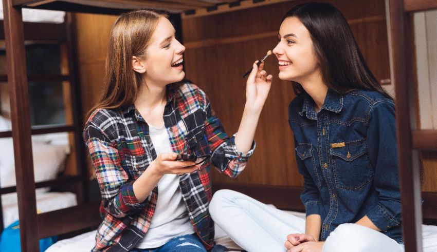 Two girls sitting on a bunk bed talking to each other.