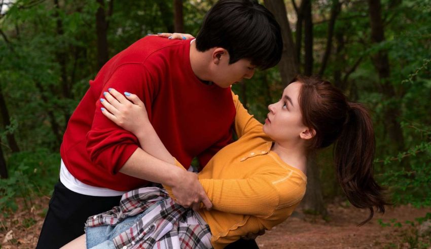 A man and woman hugging in the woods.