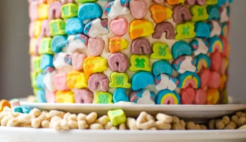 A rainbow shaped cake with marshmallows on top.
