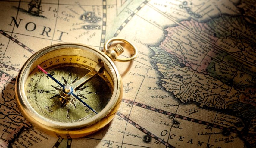 A gold compass rests on top of an old map.