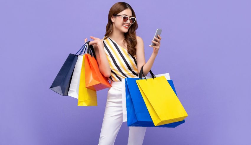 A young woman holding shopping bags and a cell phone.