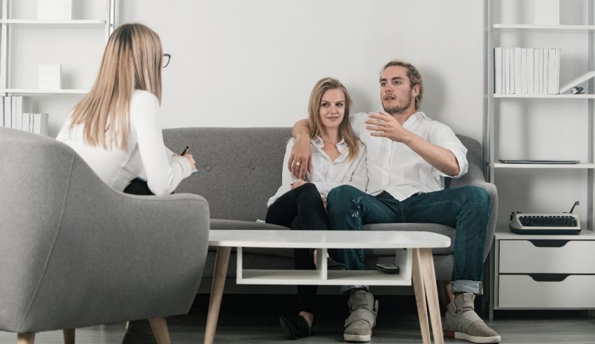 A man and woman sitting on a couch talking to each other.