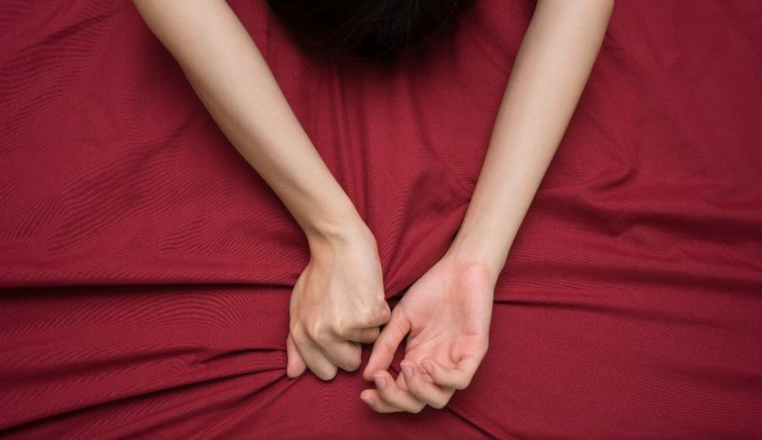 A woman is laying on a red bed with her hands wrapped around it.