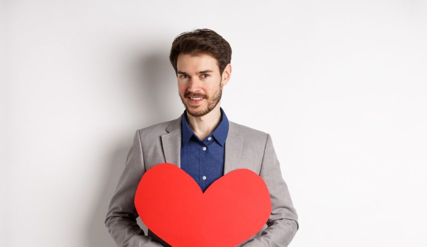A man holding a red heart on a white background.