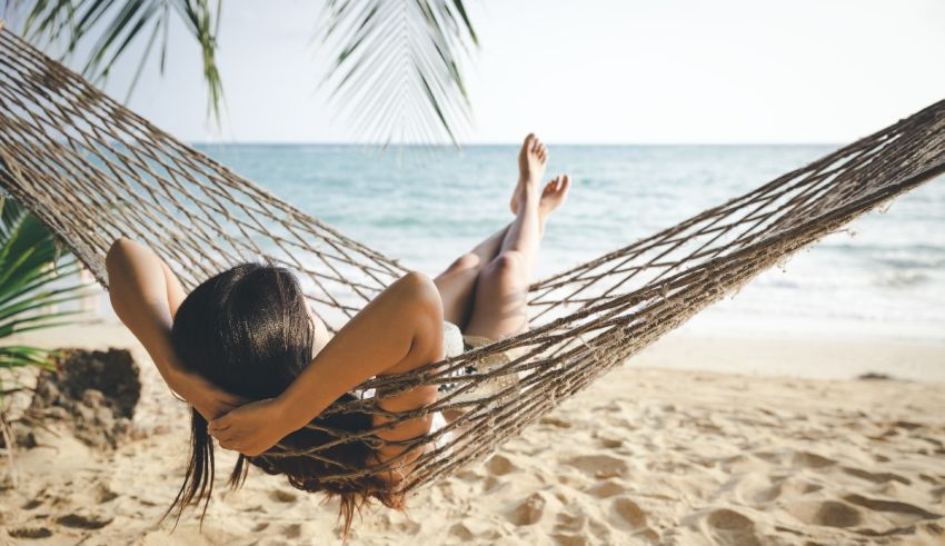 A woman relaxes in a hammock on the beach.
