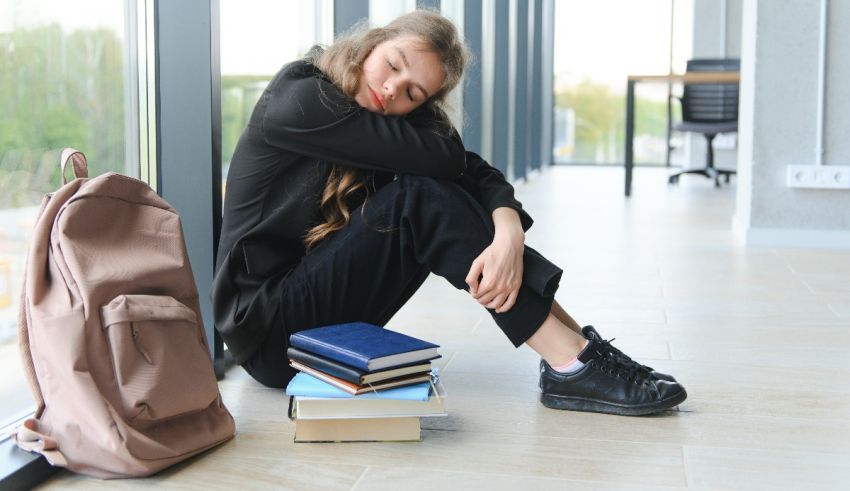 A young woman sitting on the floor with books and a backpack.