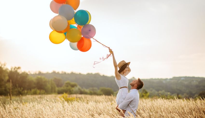 A man and woman holding balloons in a field.
