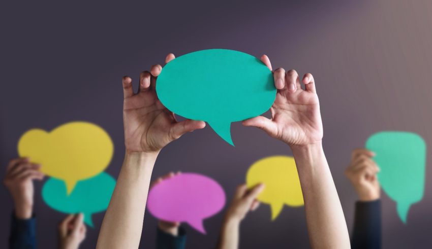 A group of people holding up colorful speech bubbles.