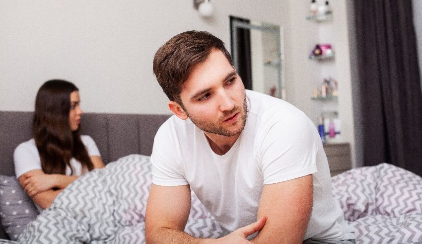 A man and woman sitting on a bed in a bedroom.