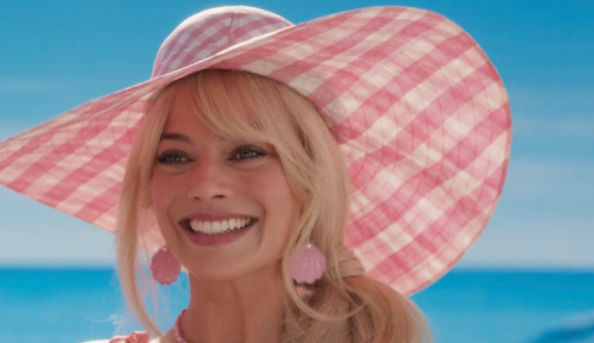 A woman in a pink hat smiling at the ocean.