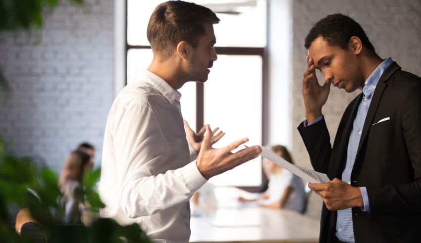 Two businessmen in an office talking to each other.